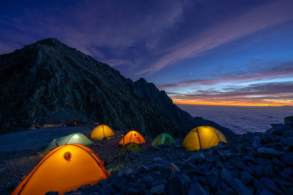 Two men are trekking the Annapurna Circuit, walking through an area where dry grasses cover the ground, while green hills rise up beside them.