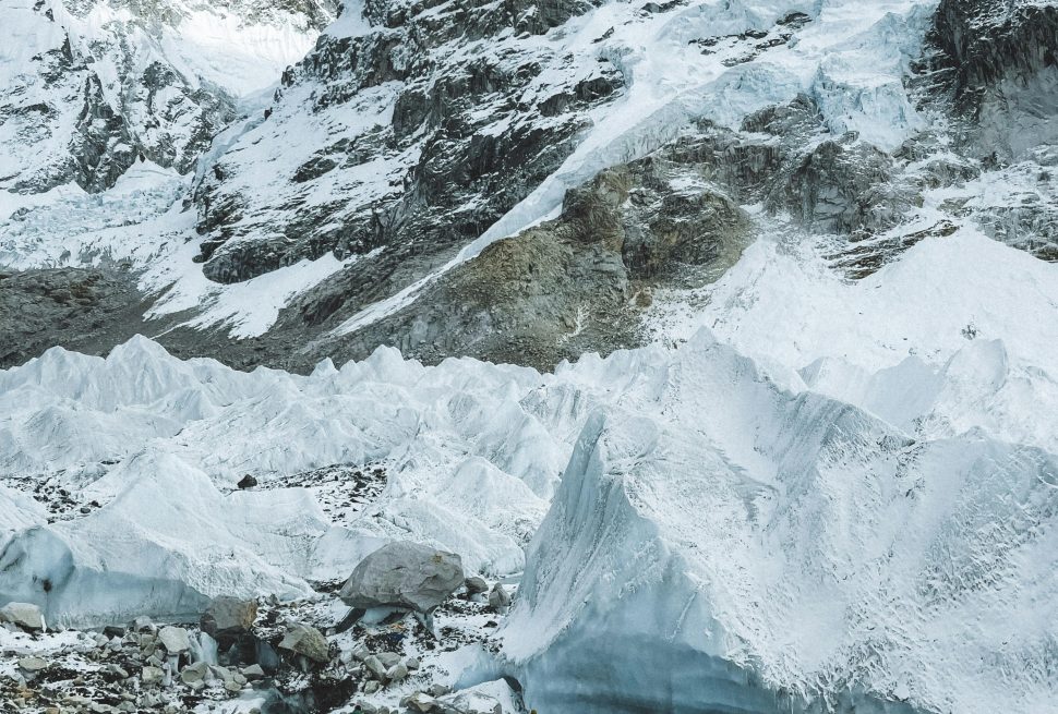 this is the picture of the everest where it is covered with the snow and covered by the clouds in the blue sky and on the base we can see the small white stones as well