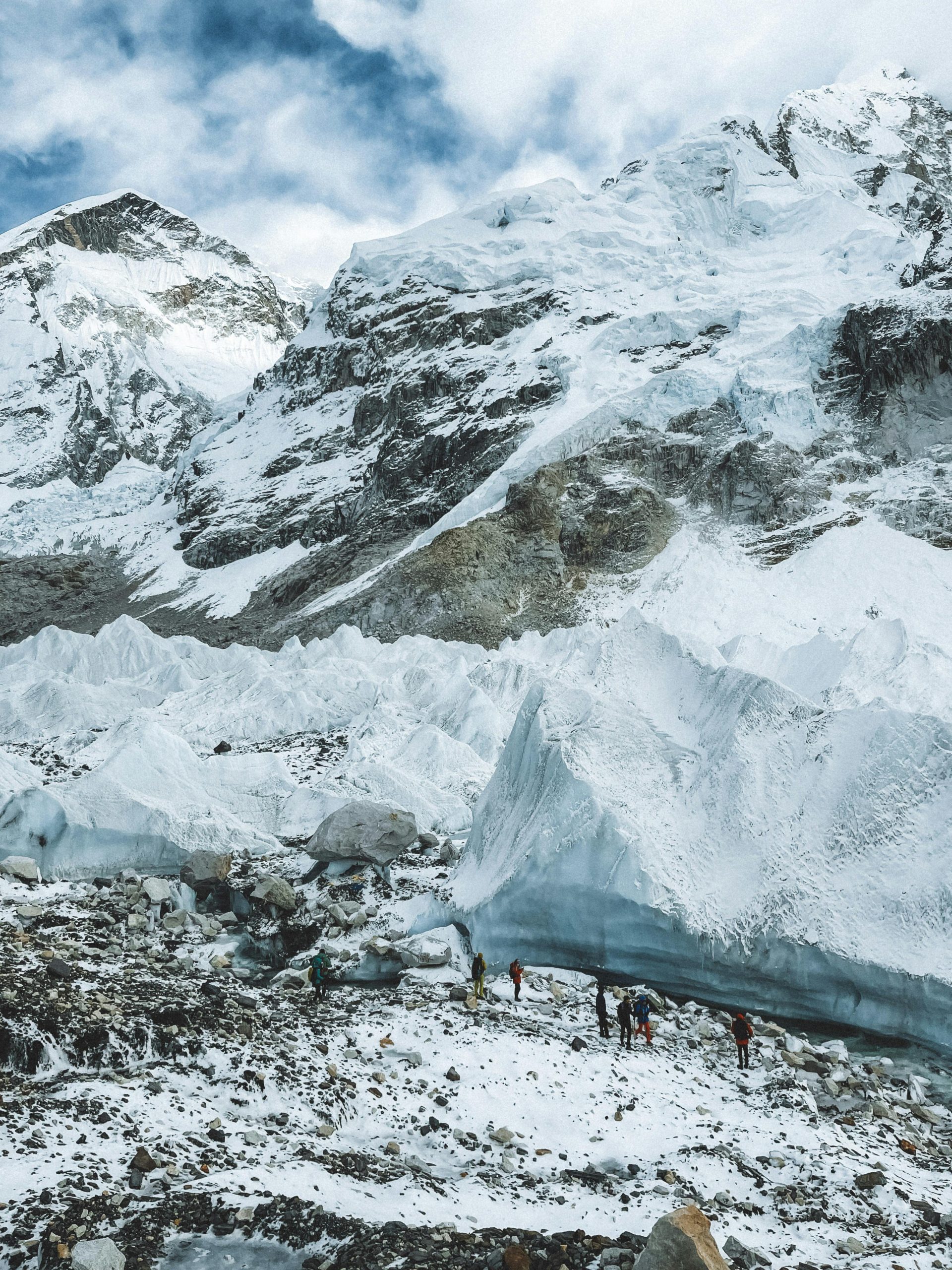 this is the picture of the everest where it is covered with the snow and covered by the clouds in the blue sky and on the base we can see the small white stones as well