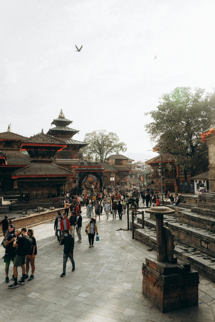 the picture is about the Kathmandu Durbar Square which the world heritage site where we can see the the statue of the "Kal Bhairav" the devotee of the death, aside the statue there is walking space for the people where many people and walking and the statue is surrounded by the different temples.