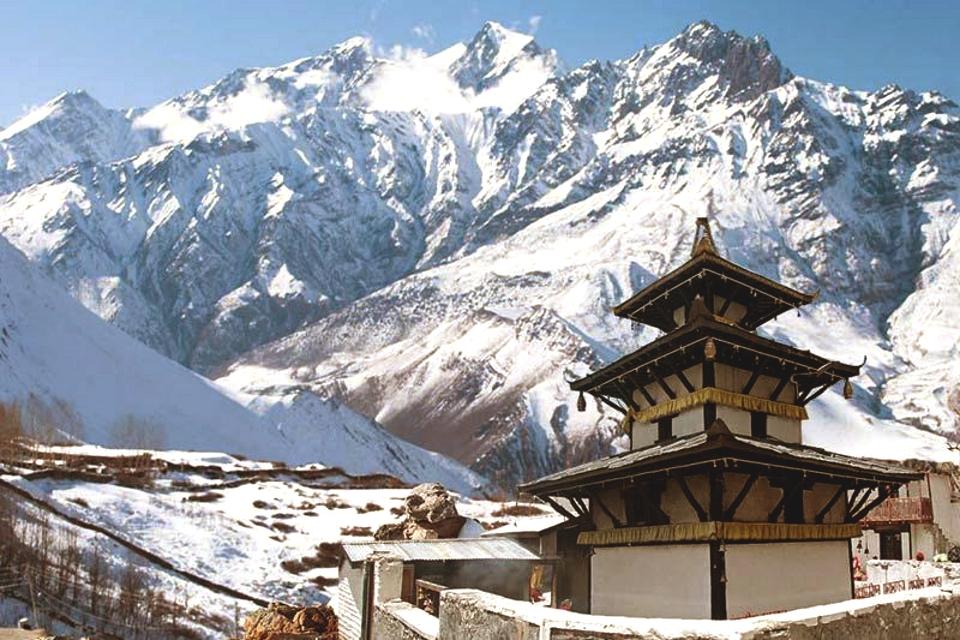 The picture depicts the Muktinath Temple, nestled amid white mountains and surrounded by a few trees.