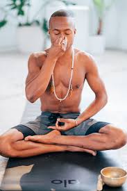 A man sits calmly on a mat, practicing pranayama in a tranquil environment.