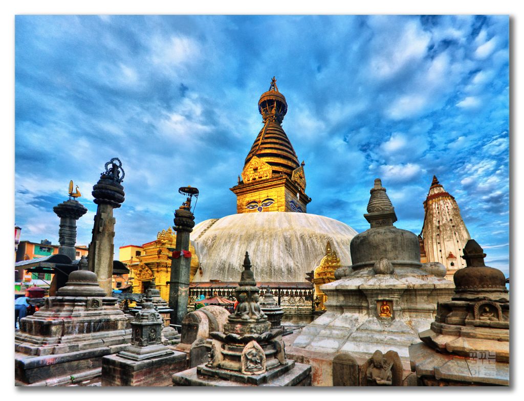 Under the blue and cloudy sky we can see the big sstupa where there is two eye and "Gajur" structure. and many other stupa are also seen there  where it makes the picture beautiful