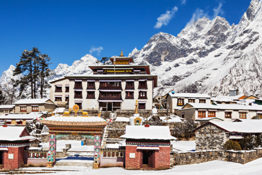 The picture showcases monasteries nestled among various small houses. These structures are all set against the backdrop of stunning mountains that encircle the area.